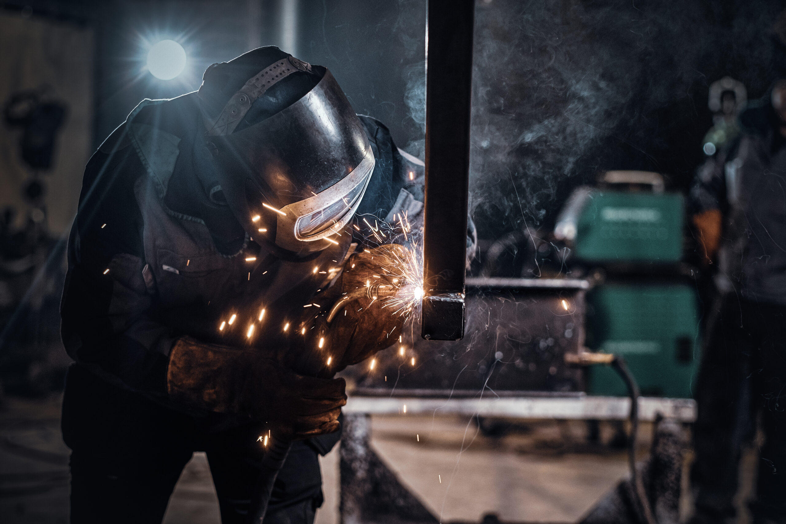 Man is working at the busy metal factory Man is working at metal factory, he is welding a piece of rail using special tools.